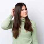 Vrouw in groene trui krabt op hoofd