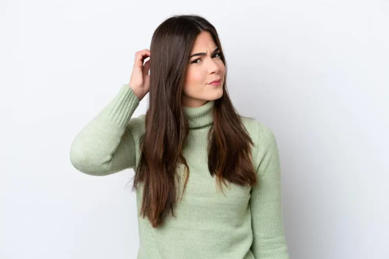 Vrouw in groene trui krabt op hoofd