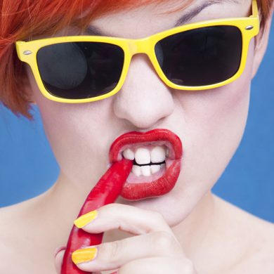 Vrouw met zonnebril bijt in een chilipeper