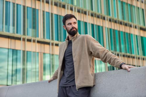 man gekleed in donkere jeans en beige jack