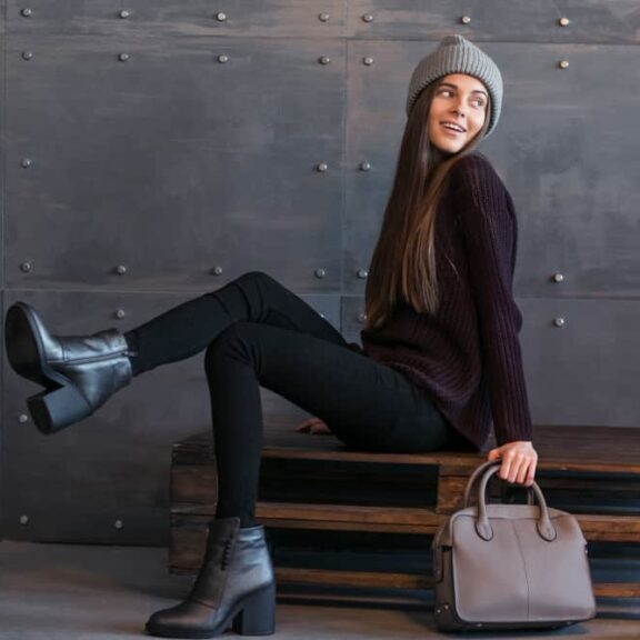 Vrouw met modieuze kleding en accessoires op bank.