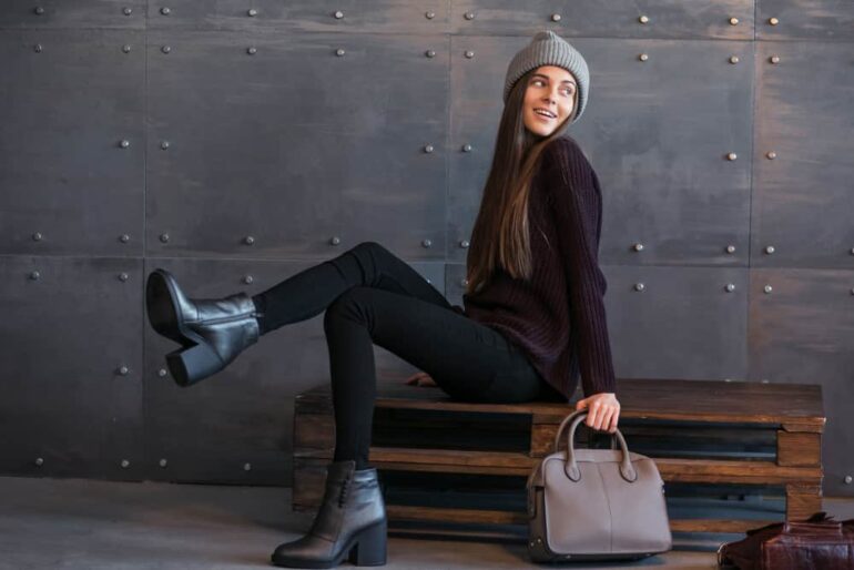 Vrouw met modieuze kleding en accessoires op bank.