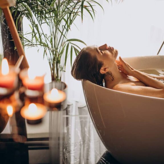 Vrouw ontspant in bad met kaarsen.