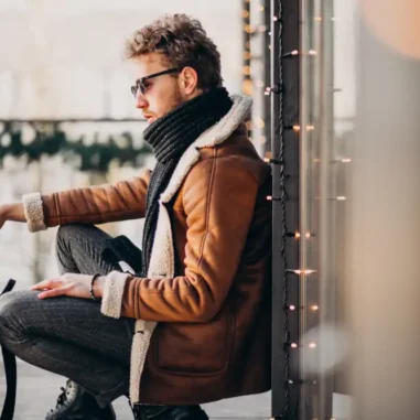 Man met zonnebril zit op terras in winterkleding.