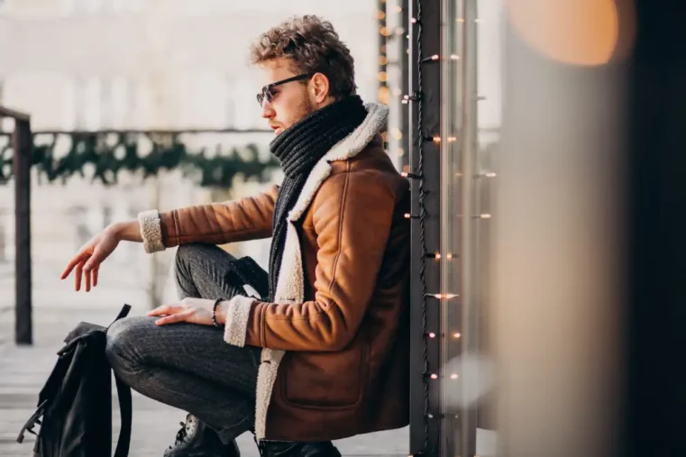Man met zonnebril zit op terras in winterkleding.