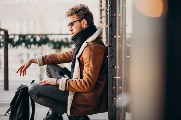 Man met zonnebril zit op terras in winterkleding.