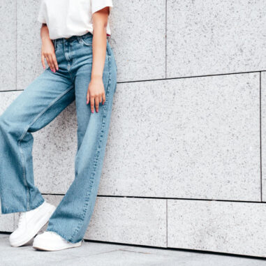 Vrouw draagt wijde spijkerbroek en sneakers.