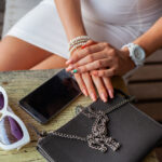 Vrouw met accessoires, handtas en zonnebril op tafel.