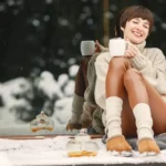 Vrouw met UGGs geniet van warme drank in de sneeuw.