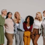 Groep lachende vrouwen van verschillende leeftijd samen in casual outfits.