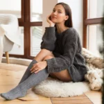 Vrouw in comfortabele sweater zit op vloerbedekking