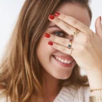 vrouw kijkt door vingers met gouden ringen