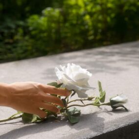 vrouw legt bloem op graf bij uitvaart