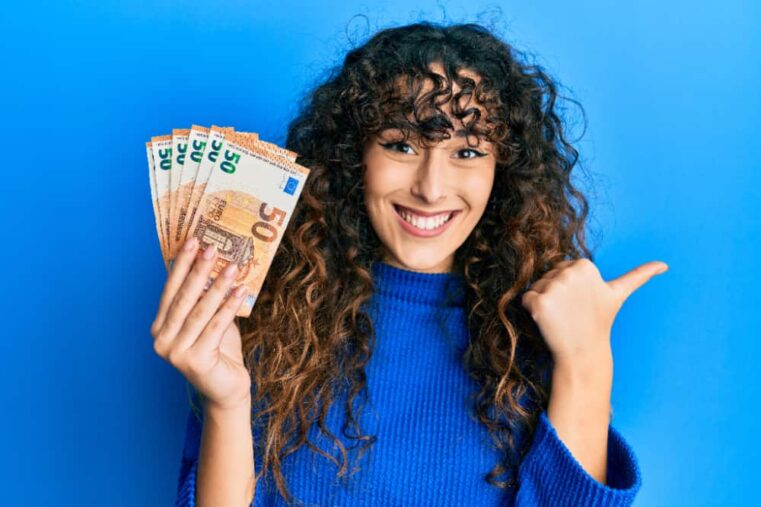 jonge vrouw kijkt blij met briefjes van 50 euro