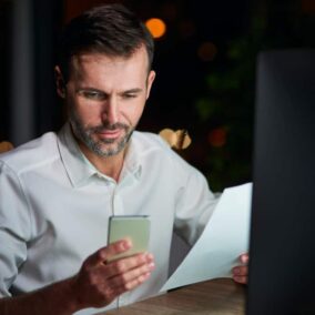 man houdt mobiel vast en een papier