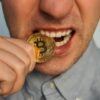 man bijt op bitcoin munt