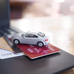 laptop met betaalpassen en miniatuur auto