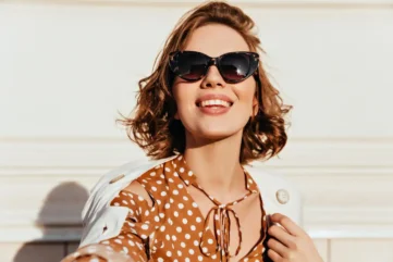 Vrouw met zonnebril kijkt naar de zon