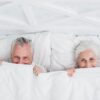 twee senioren in comfortabel bed met wit beddengoed