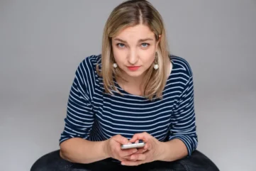 vrouw kijkt somber met mobiel in de hand