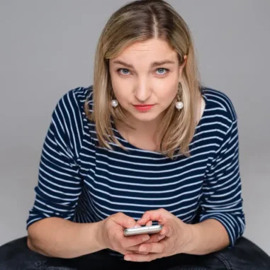 vrouw kijkt somber met mobiel in de hand
