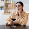 vrouw zit alleen aan keukentafel te drinken