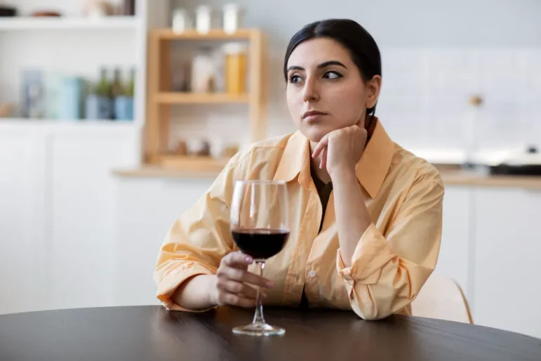 vrouw zit alleen aan keukentafel te drinken