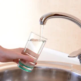 hand van vrouw met glas die water uit kraan tapt