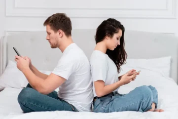 Man en vrouw met rug naar elkaar toe op mobiele telefoon bezig