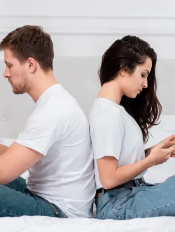 Man en vrouw met rug naar elkaar toe op mobiele telefoon bezig