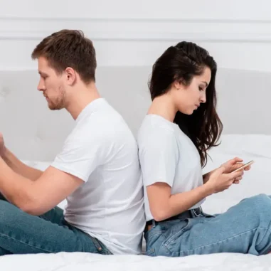 Man en vrouw met rug naar elkaar toe op mobiele telefoon bezig