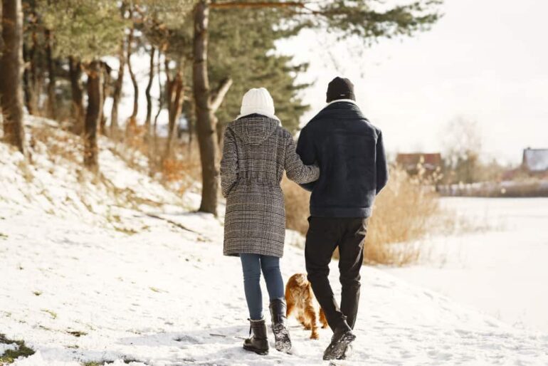 man en vrouw wandelen met hond in de winter