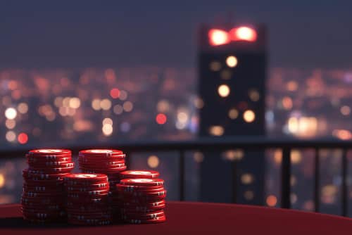 Pokerfiches op tafel met stadslichten op achtergrond.