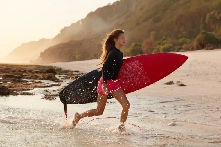 Vrouw rent met surfplank op strand