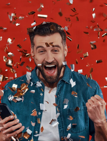 Blije man viert jackpot met confetti en smartphone