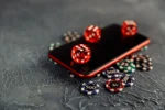 Smartphone met dobbelstenen en casinofiches op tafel.