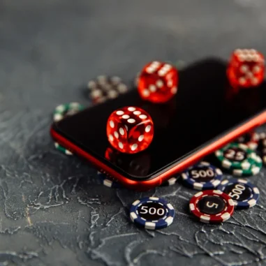 Smartphone met dobbelstenen en casinofiches op tafel.
