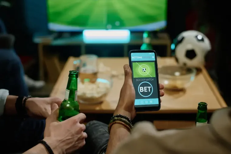 Mensen kijken voetbal op tv en wedden op mobiel.