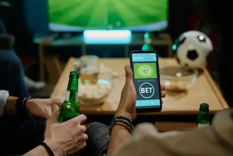 Mensen kijken voetbal op tv en wedden op mobiel.