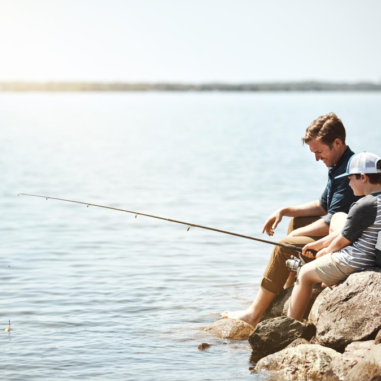 Vader en zoon vissen samen bij het meer.