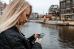Vrouw gebruikt smartphone bij Amsterdamse gracht