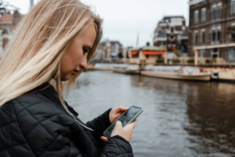 Vrouw gebruikt smartphone bij Amsterdamse gracht