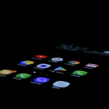 Smartphone met verlichte apps in donkere omgeving.