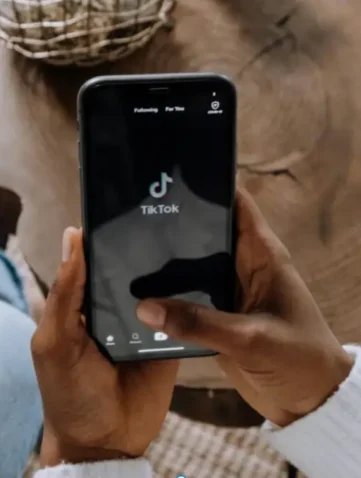 Persoon houdt smartphone met TikTok-app vast.