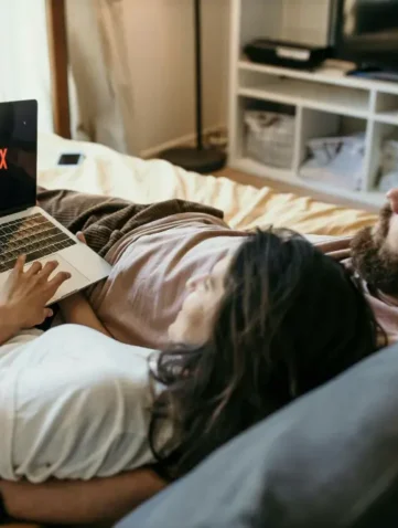 Stel kijkt Netflix op laptop in bed
