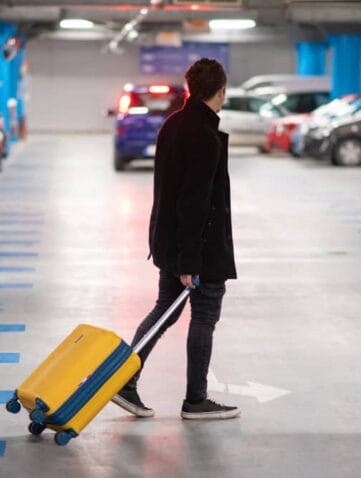Man met koffer loopt door parkeergarage