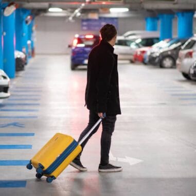 Man met koffer loopt door parkeergarage