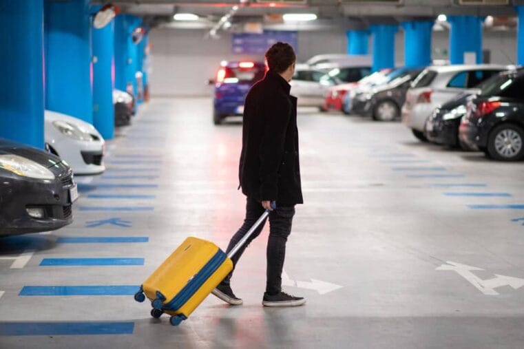 Man met koffer loopt door parkeergarage
