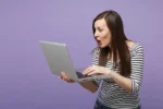Vrouw kijkt blij verbaasd op haar computer.