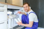 man installeert waterontharder in aanrechtkastje